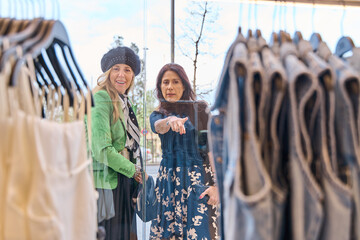 mature friends looking through a shop window at clothes to buy