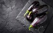Fresh ripe eggplant with droplets of water on a stone board. On a black background