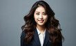 © Bartek - Professional young Asian businesswoman in navy blue suit with confident smile against a neutral grey backdrop