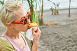 © Caterina Trimarchi - Young blond woman at seaside eating hot palatable arancini (deep fried rice balls with meat). Typical Sicilian street food. Close up.