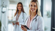 © Studio Nova - smiling female healthcare professional in the foreground holding a clipboard with a stethoscope around her neck
