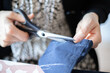 © AAlves - Detail of the hands of a caucasian woman doing sewing work in her home. Process and execution. Measuring, cutting and sewing to re-hem a pair of trousers.