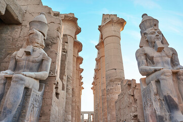 Seated statue of Ramesses II by the First pylon of the Luxor Temple, Egypt. Columns and statues of the Luxor temple main entrance, first pylon, Egypt