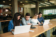 © Aleksandr - Group of college students studying in the school library, a girl and a boy are using a laptop and connecting to internet