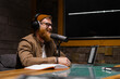 © Big Shot Theory - Smiling and gesturing radio host with headphones reading news into studio microphone