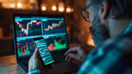 Poster - a person is holding a smartphone with stock market data on the screen, with a blurred background showing a computer monitor with financial graphs