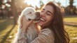 beautiful woman laughing while her pet is licking her face in a sunny day in the park in Madrid. The dog is on its owner between her hands. Family dog outdoor lifestyle
