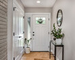 © Joseph Hendrickson - A cozy entryway with brown and brick walls, hardwood flooring, decorations, and a white front door with windows.