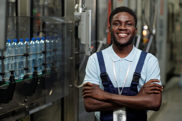 Poster - young successful african american inspector in workwear looking at camera with smile while standing 