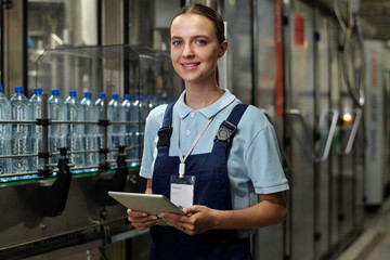 Poster - young successful engineer or inspector with tablet looking at camera while standing in industrial pl