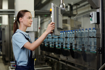 Poster - young quality control inspector looking at screen while standing in front of factory equipment with 