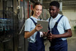 © pressmaster - Two young confident quality control inspectors in workwear looking at screen of tablet held by woman while discussing data