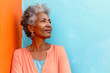 Afroamerican famele with grey hair and in casual outfit against blue and orange wall