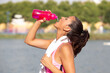 Mujer deportista bebiendo hidratándose después de hacer ejercicio al aire libre