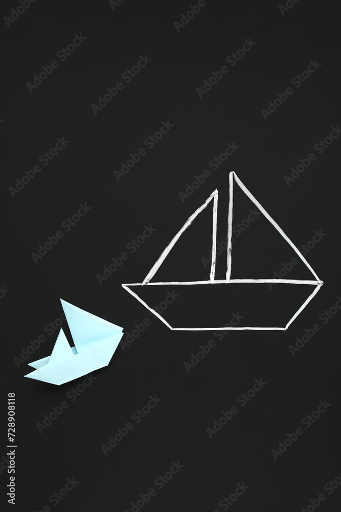 Drawn and colorful paper boats on black chalkboard