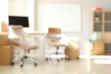 Sticker - Blurred view of office with chairs wrapped in stretch film and cardboard boxes on moving day