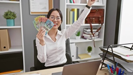 Sticker - Excited young chinese woman celebrates victory in office, proudly raises australian dollars, reveling in business success!