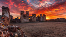 Underneath The Vibrant Colors Of A Sunset Sky The Ruins Of An Old Fort Are A Striking Sight.