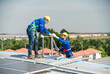 © Hip.hub - Male technicians holding solar panels on factory roofs and Engineers in helmets are helping each other as a team. Could you install an outdoor solar panel system or an Alternative solar cell.