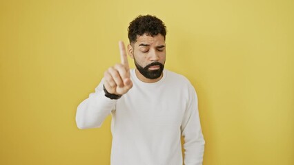 Sticker - Hispanic young man, standing against an isolated yellow background, pointing a finger up in displeasure - showing a stern 'no' gesture with a seriously angry expression.