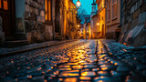 Fototapeta Uliczki - A narrow cobblestone street in an old town, lined with historic buildings and lit by warm street lamps at dusk