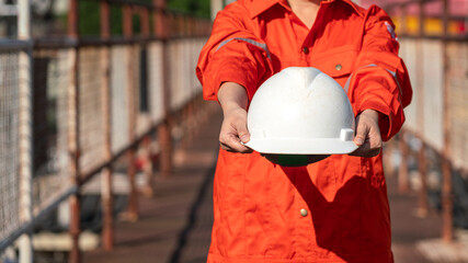 Wall Mural - Action of a supervisor is giving white safety hardhat or helmet to the camera, Safety first working in risk industrial workplace concept scene. 