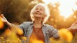 A happy elderly woman greeting the sun with hands in the air against a blooming field backdrop. Gratitude and harmony with nature concept.