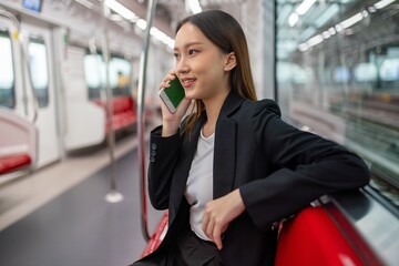 Asian businesswoman talking on phone while on the way traveling to the airport in a metro skytrain