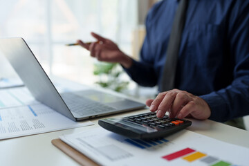 Wall Mural - Asian businessman points at laptop computer screen to calculate budget, financial statistics and discuss financial services and management issues.