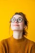 Studio portrait of young woman with glasses on yellow background