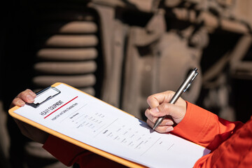 Wall Mural - action of a mechanic engineer is checking on heavy machine checklist form to verify the quality of m