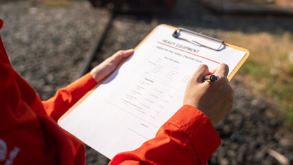 Wall Mural - action of a mechanic engineer is checking on heavy machine checklist form to verify the quality of m