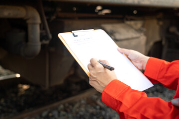 Wall Mural - action of a mechanic engineer is checking on heavy machine checklist form to verify the quality of m