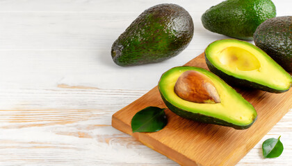 Board with fresh ripe avocados on white wooden background copy space