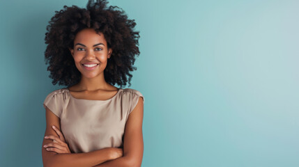 Wall Mural - woman with curly hair is smiling at the camera, standing with her arms crossed in front of a light blue background