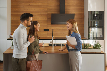 Female shop assistant helping young couple choose new kitchen appliance