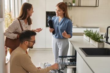 Female shop assistant helping young couple choose new dishwasher