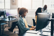 © Flamingo Images - Young businesswoman using a computer with colleagues working in the background