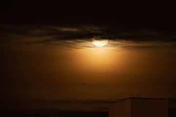Wall Mural - The Moon in the sky in dark clouds surrounded by yellow light is a multiple moonlight in the atmosphere. Full moon in the style of mystical and thriller films