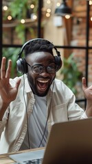 Wall Mural - Black male with an enthusiastic expression wearing headphones and raising his hands up while looking at his laptop, background image, generative AI