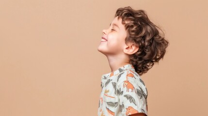 Wall Mural - A young child with curly hair smiling and looking up wearing a white shirt with playful animal prints.