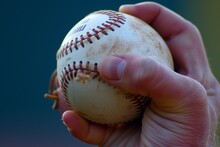 closeup of pitchers hand gripping baseball with seams visible