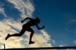 low angle of hurdler silhouetted against the sky