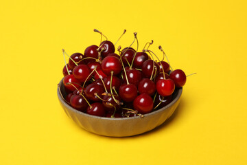 Sticker - Ripe cherry fruits in a bowl on a yellow background