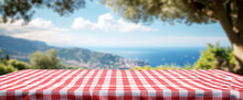 A Picnic Table With A Red And White Checkered Tablecloth And A View Of The Ocean