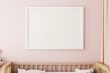 white frame on a light pink wall in a nursery, crib underneath