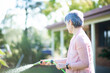 © Austockphoto - Middle aged woman watering her garden beside her house