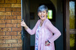 © Austockphoto - happy senior woman standing at her front door to welcome visitors