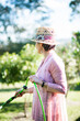 © Austockphoto - Happy senior woman watering trees in her garden in spring