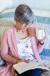 © Austockphoto - Happy woman reading a book while drinking a cuppa tea